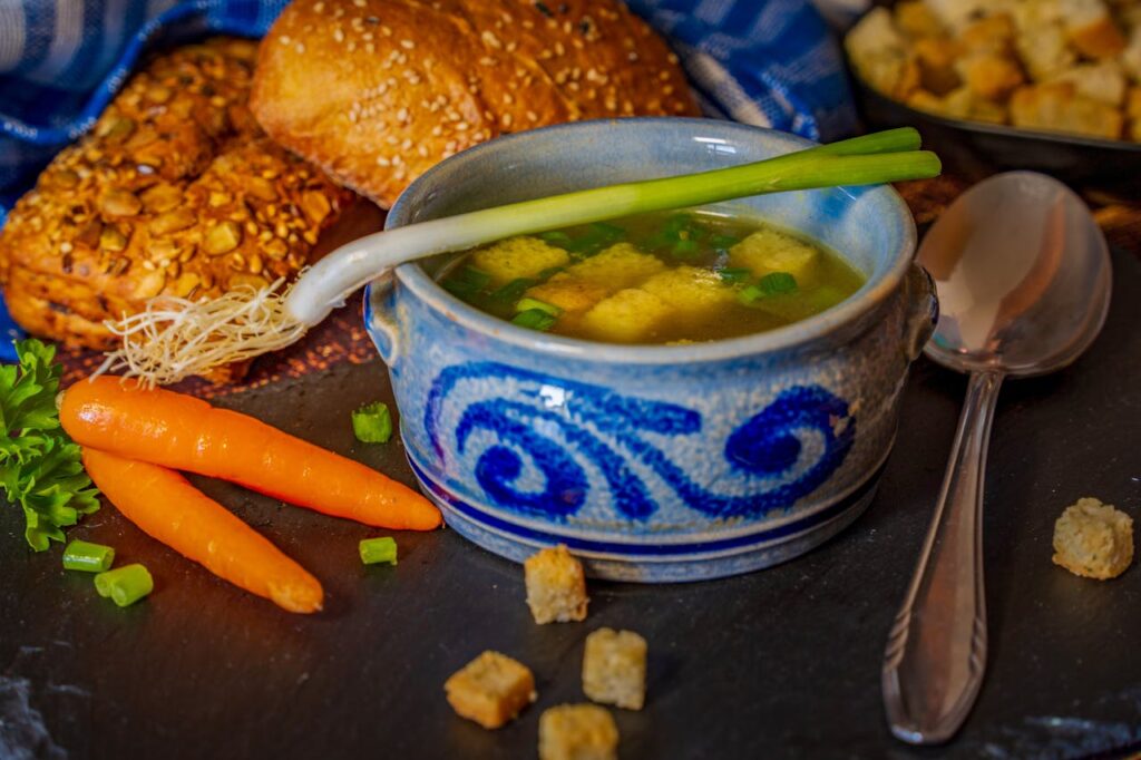 Cozy bowl of vegetable broth with croutons and bread, perfect for winter comfort.