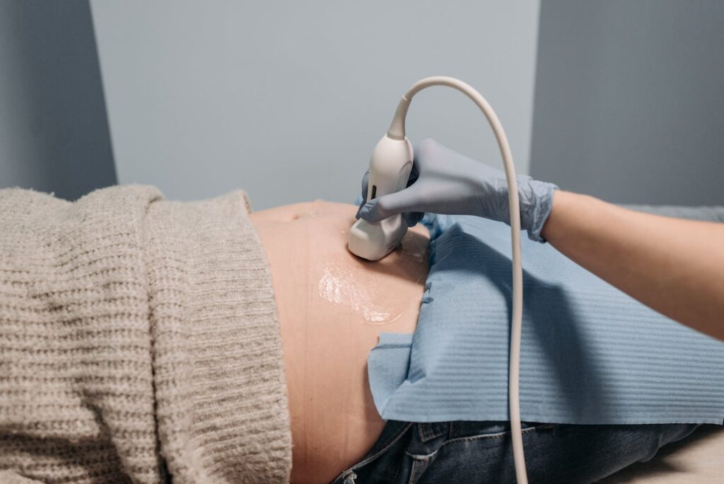 A healthcare professional performing an ultrasound on a pregnant abdomen.